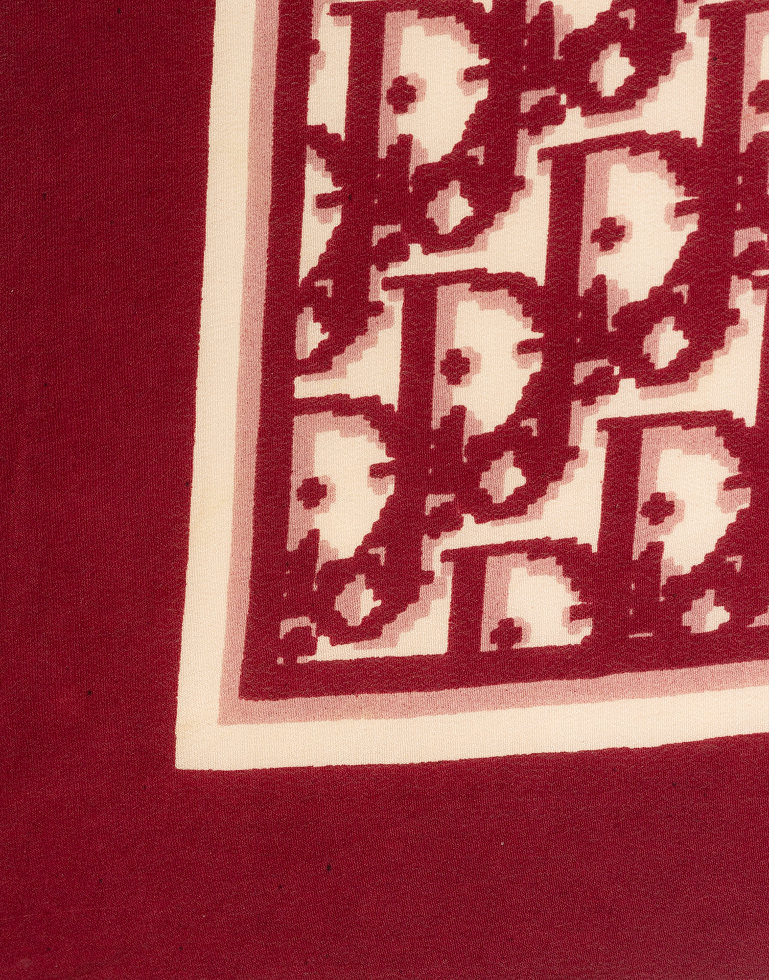 Red monogram scarf, photographed on a gray background.