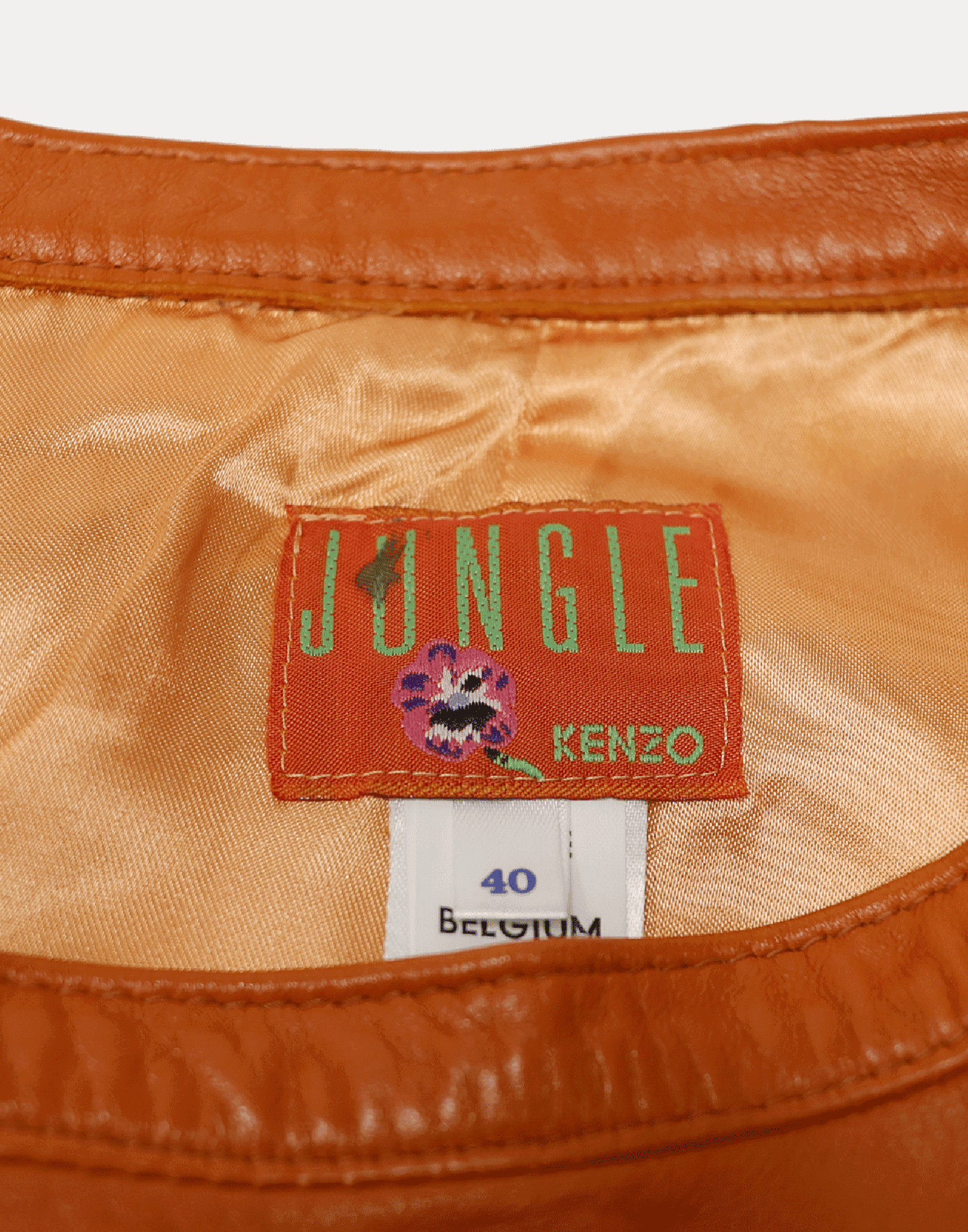 Flared orange leather skirt with back zip and button closure. Photographed on a ghost mannequin against a gray background.
