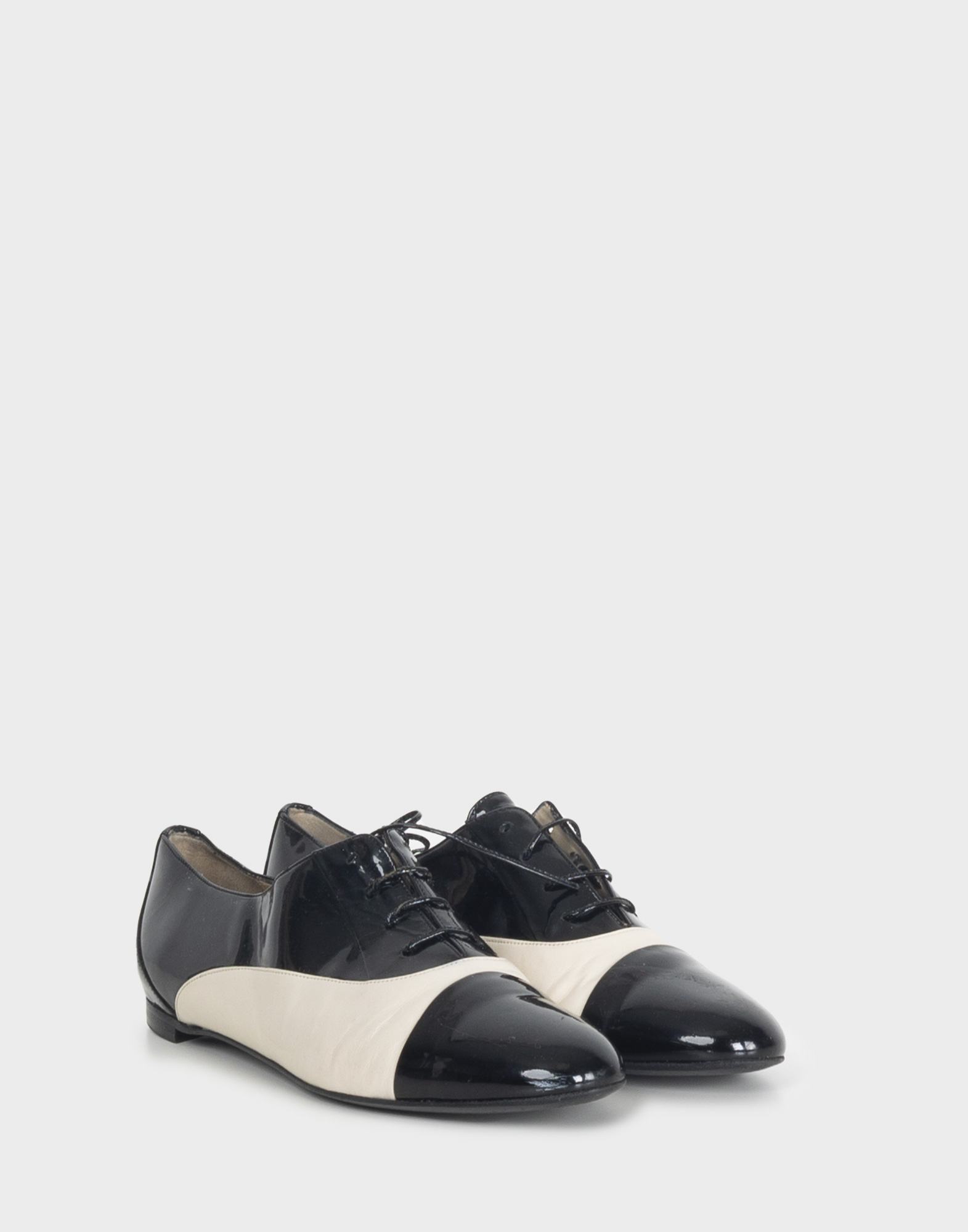 Women's black and white patent leather derby shoes with a round toe and laces.