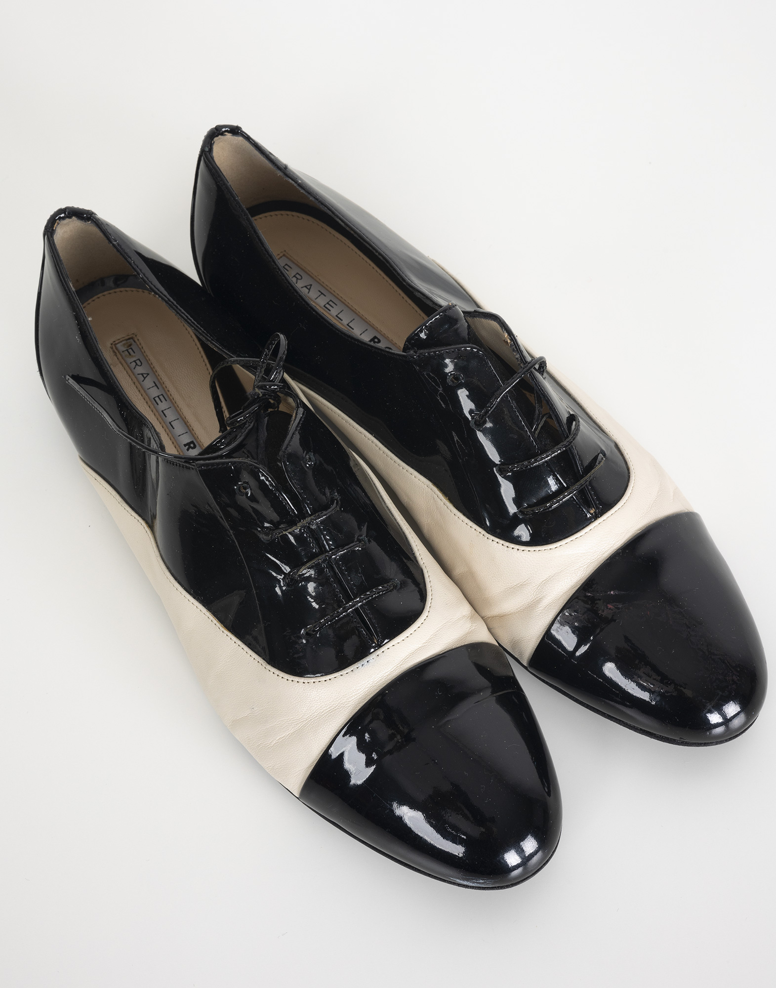 Women's black and white patent leather derby shoes with a round toe and laces.