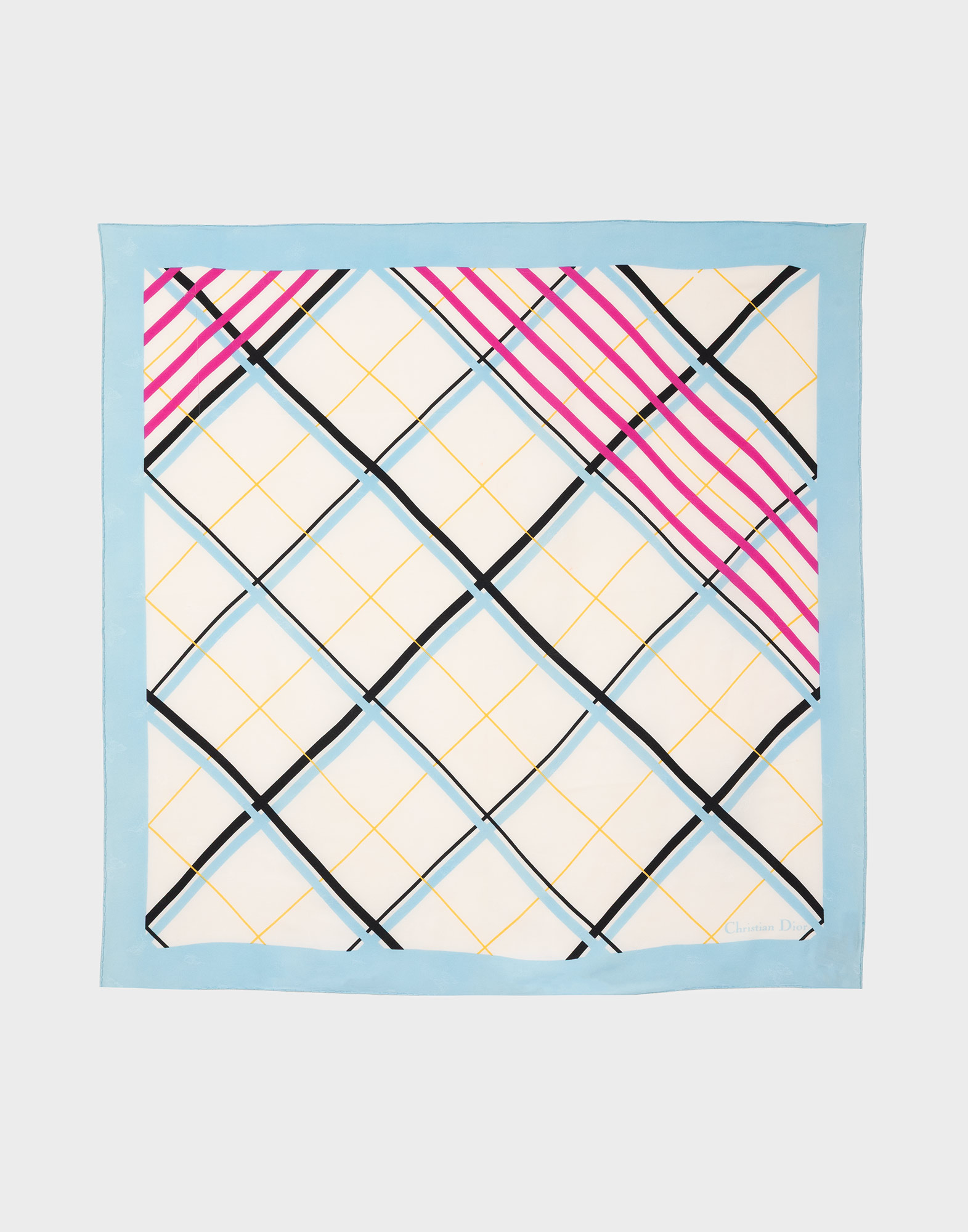 Square silk scarf with argyle pattern on a cream background, light blue edges, pink and black diagonal lines, and a "Christian Dior" signature in the lower right corner.